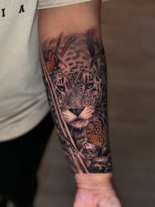 Leopard, jaguar or jeopard with butterflies in the savannah tattoo realism bushwick